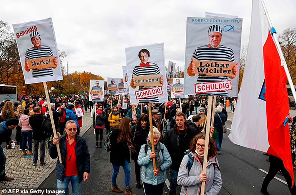 Demonstrators hold placards featuring (L-R) German Chancellor Angela Merkel, SPD politician Karl Lauterbach and the head of the Robert Koch Institute (RKI) Lothar Wieler with the inscription guilty during a protest against measures imposed by the German government to limit the spread of the novel coronavirus, on November 18, 2020